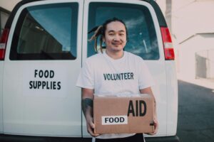 A volunteer holding a box labeled "food" in front of a van