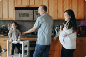 Family (father, pregnant mother, and toddler in a high chair) in the kitchen